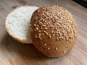 Closeup of a hamburger bun with sesame seeds, cut in half to show the breadcrum