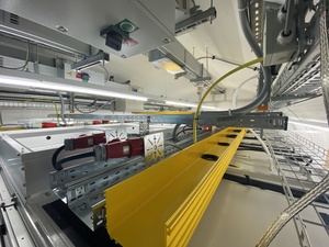 A view of the top of the racks with the cold aisle roof in front of us, and a bright yellow fibertray that will carry the fiber trunks between the racks.